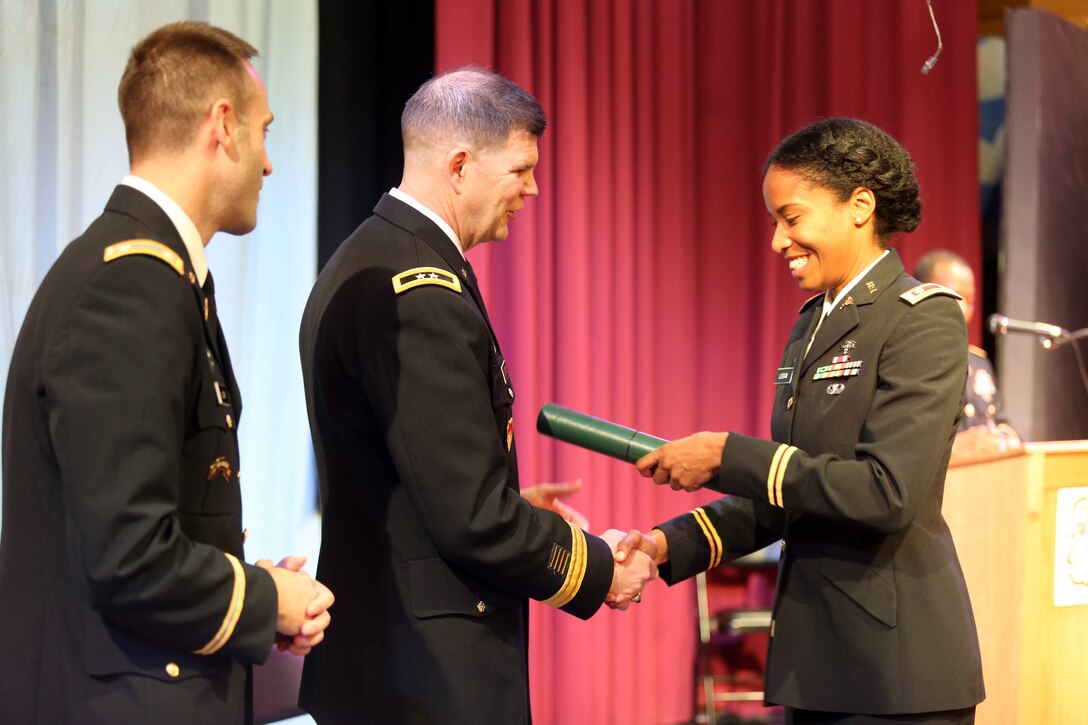 Maj. Kourtney Logan looks down at her graduation certificate presented by Maj. Gen. Todd B. McCaffrey, U.S. Africa Command chief of staff, during a U.S. Army Command and General Staff Officers Course Common Core graduation ceremony hosted by the 7th Intermediate Level Education Detachment, 7th Mission Support Command, in Grafenwoehr, Germany, May 17, 2019. The 7th ILE DET offers a unique year-long ILE common core curriculum designed for multi-component officers deployed or stationed overseas.