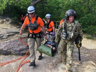 Staff Sgt. Jeremy Lowe with Charlie Company, 2nd Battalion, 238th Aviation and members of the Wolfe County Search and Rescue transport a patient to UH-60 Black Hawk for a medical evacuation in Slade, Ky., May 18, 2019. The Guardsmen responded to a request for assistance from Wolfe County Emergency Management to conduct a hoist rescue from a cliff at Natural Bridge State Park.