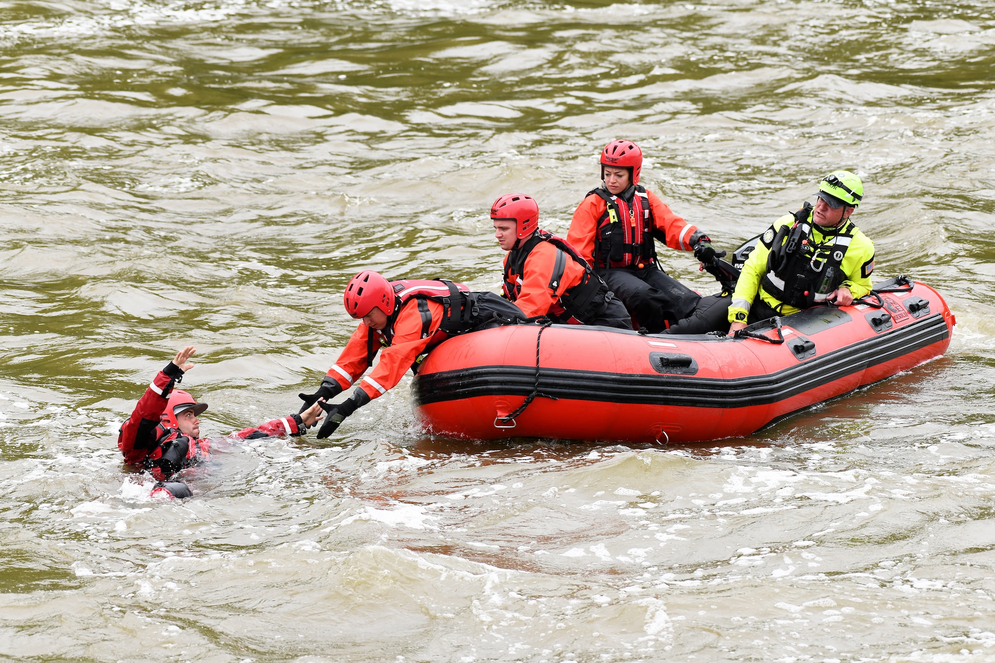 photo of Airmen on boat rescuing victim in water during training exercise