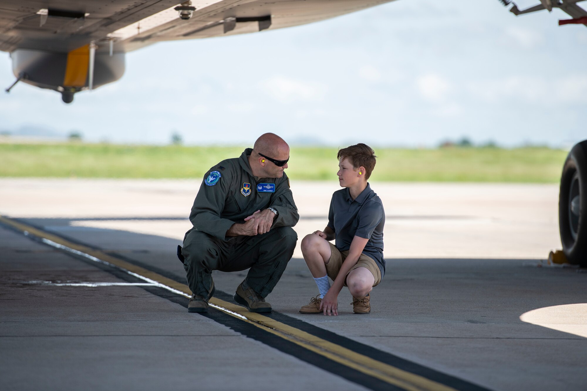 U.S. Air Force Col. Eric Carney, 97th Air Mobility Wing Commander, and his son sit under one of the newly arrived KC-46 Pegasus, May 18, 2019, at Altus Air Force Base, Okla. This new addition of aircraft will allow Altus AFB to continue its mission of training pilots and aircrew. (U.S. Air Force photo by Airman 1st Class Breanna Klemm)