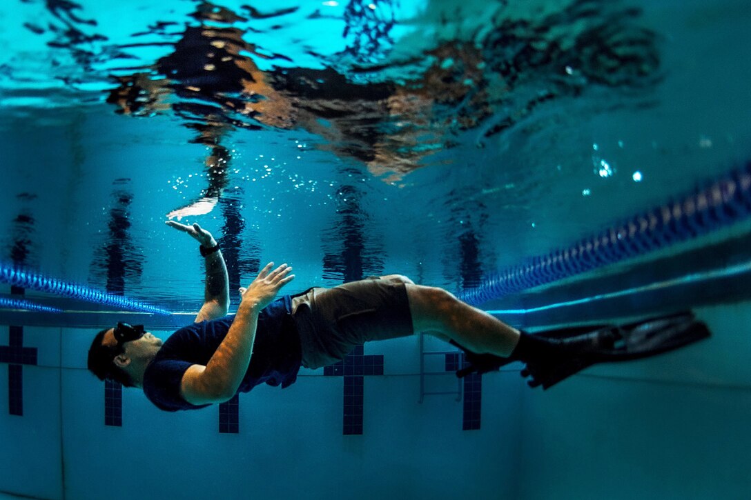 A sailor practices swimming drills while underwater.