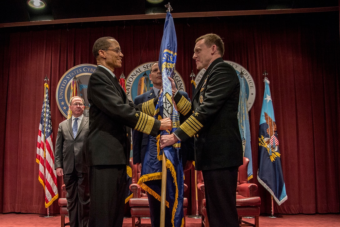 ADM Michael Rogers, USN, accepts the U.S. Cyber Command Flag from ADM Cecil Haney, USN, Commander, U.S. Strategic Command, as he assumes command, 03 April 2014