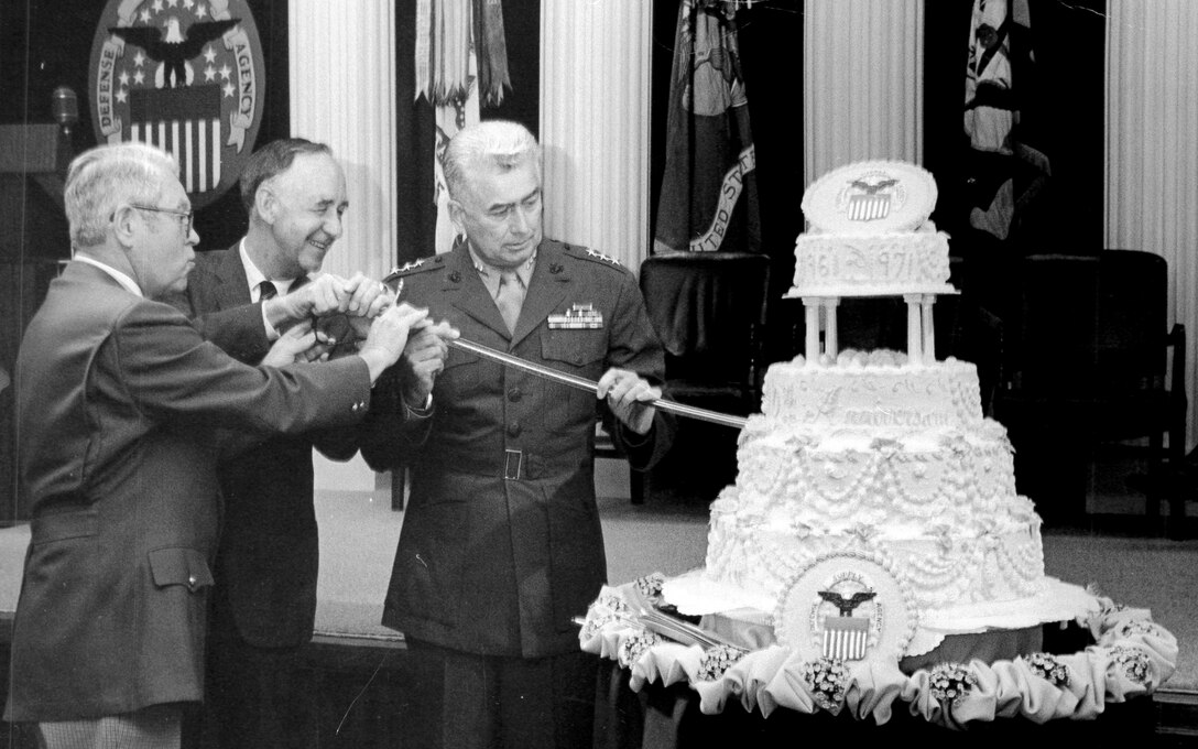 Former Defense Supply Agency directors Army Lt. Gen. Andrew T. McNamara, Navy Vice Adm. Joseph M. Lyle and Marine Lt. Gen Wallace H. Robinson, Jr. cut a cake