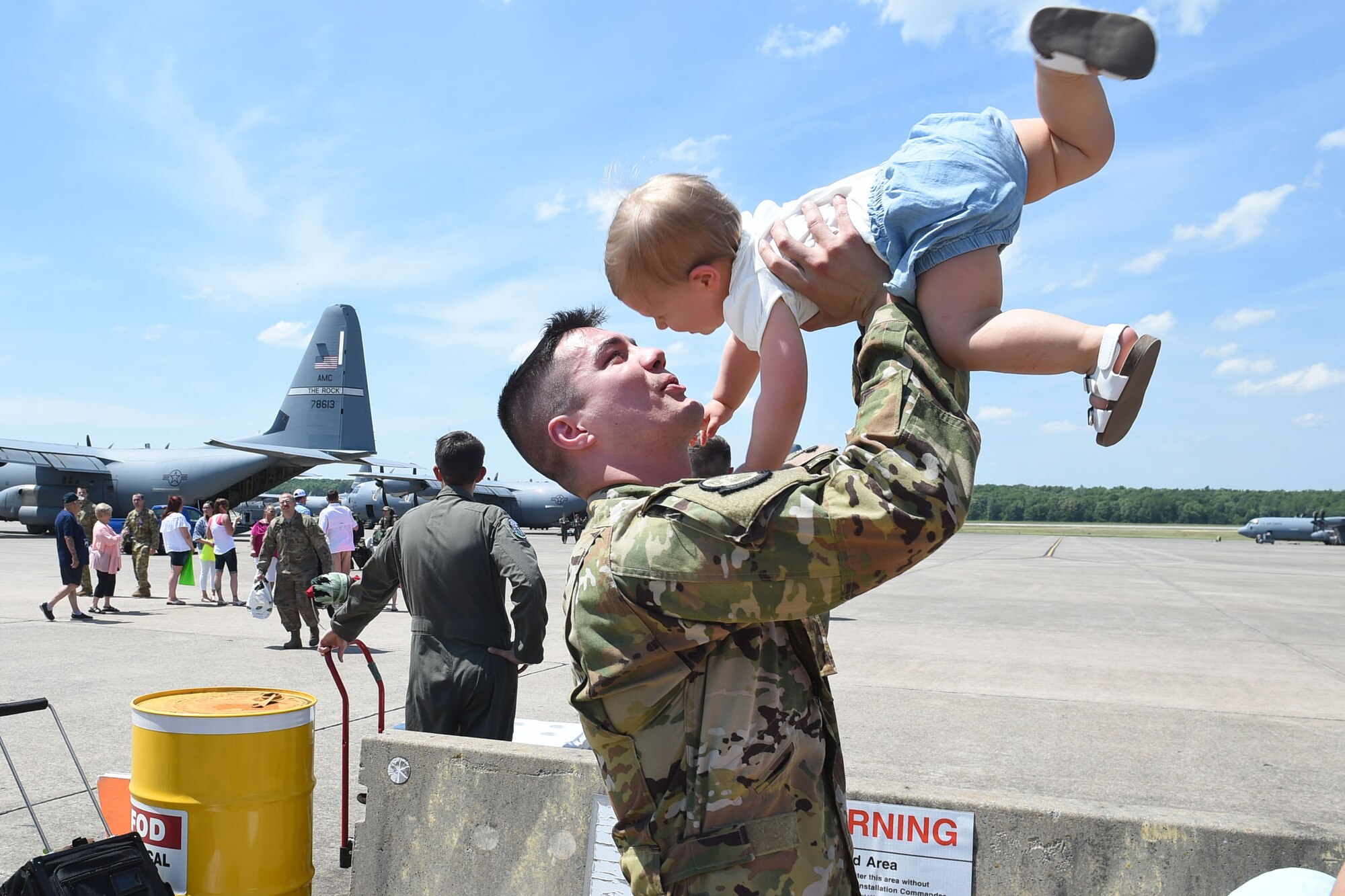 An Airman holds his small child in the air