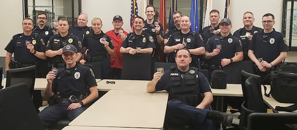 Swing Shift at Police Department posing with coin, some sitting, some standing