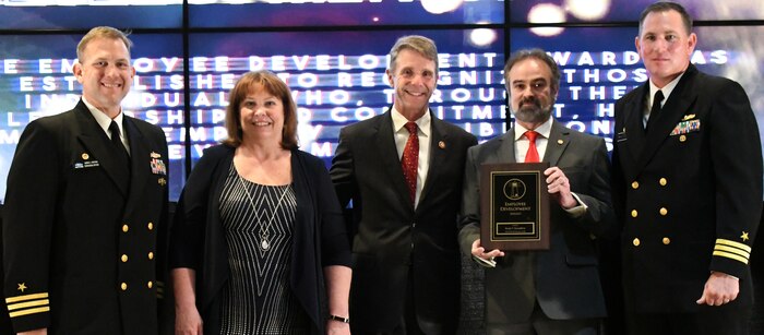 IMAGE: Brady Roundtree holds the Employee Development Award moments after receiving it from Naval Surface Warfare Center Dahlgren Division (NSWCDD) leadership at the command’s annual honor awards ceremony. Standing left to right: NSWCDD Dam Neck Activity Commanding Officer Cmdr. Andrew Hoffman; NSWCDD Deputy Technical Director Angela Beach; U.S. Rep. Rob Wittman; Roundtree; and NSWCDD Commanding Officer Cmdr. Stephen ‘Casey’ Plew. (U.S. Navy photo/Released)