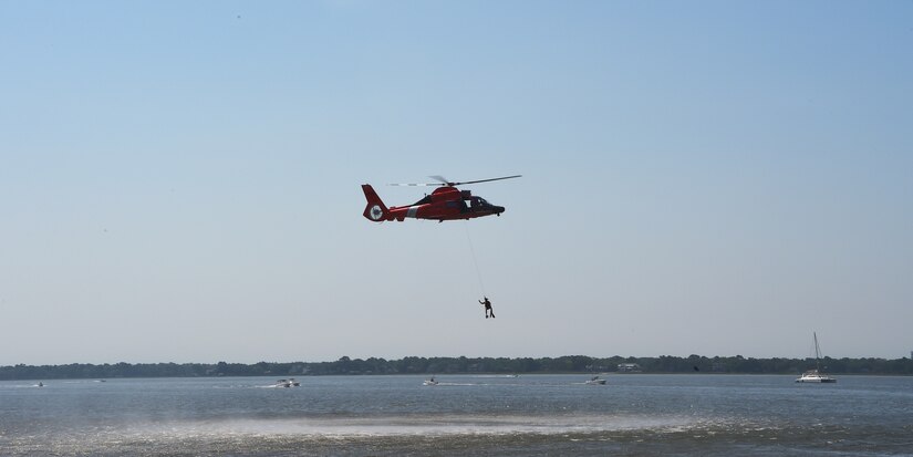 A U.S. Coast Guard aviation survival technician takes part in a rescue demonstration while hanging from a MH-65 Dolphin rescue helicopter during the National Safe Boating Week Open House May 18, 2019, at U.S. Coast Guard Sector Charleston in Charleston, S.C. The Coast Guard National Safe Boating Week Campaign is an annual week-long event held every May to promote boating safety and to inform the public on proper boating procedures. Federal law mandates that the U.S. Coast Guard establish the National Boating Safety Advisory Council and consult with it on regulations and other major boating safety matters. (U.S. Air Force photo by Senior Airman Cody R. Miller)