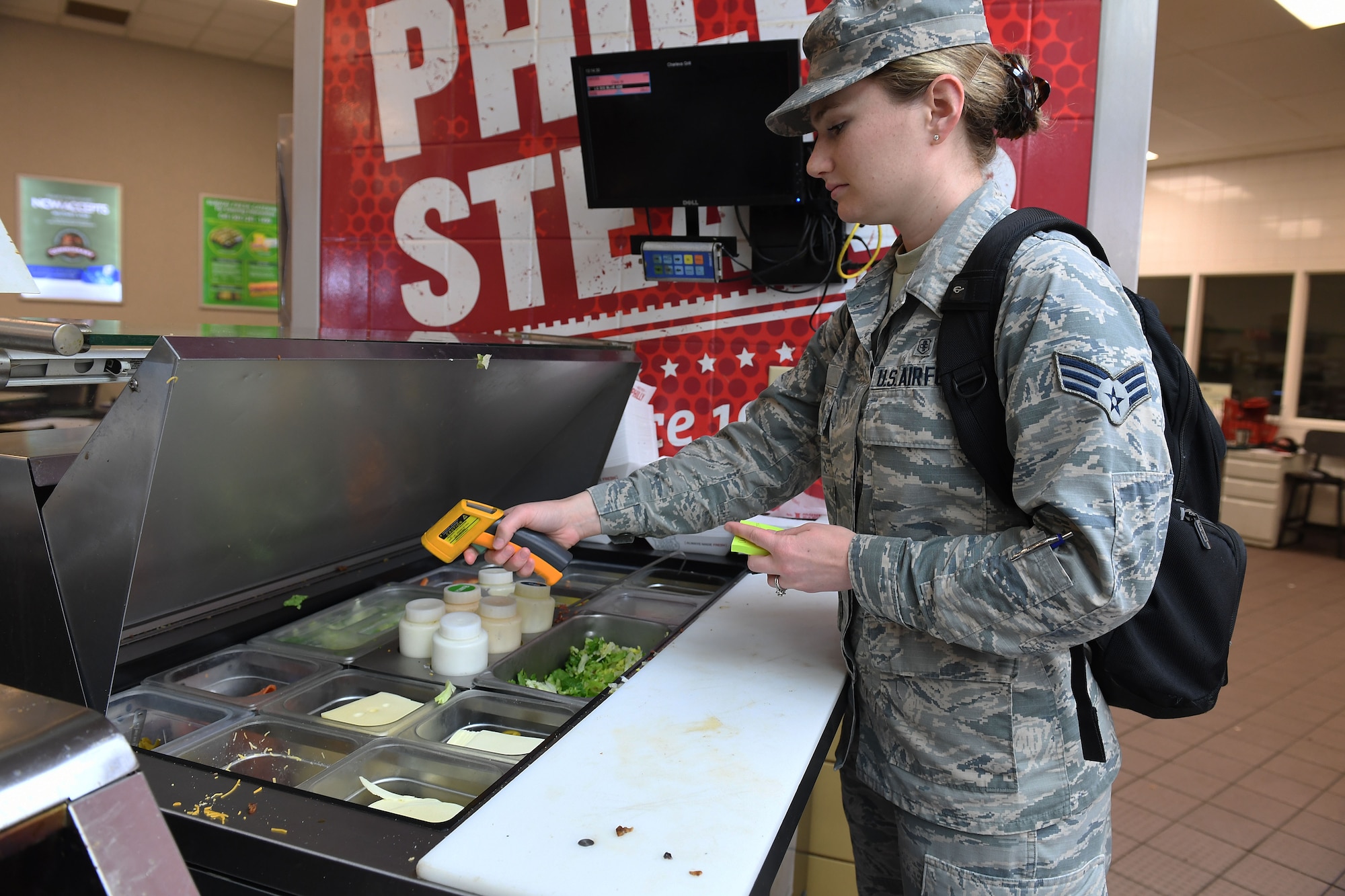 A woman points a temperature reading device at food.
