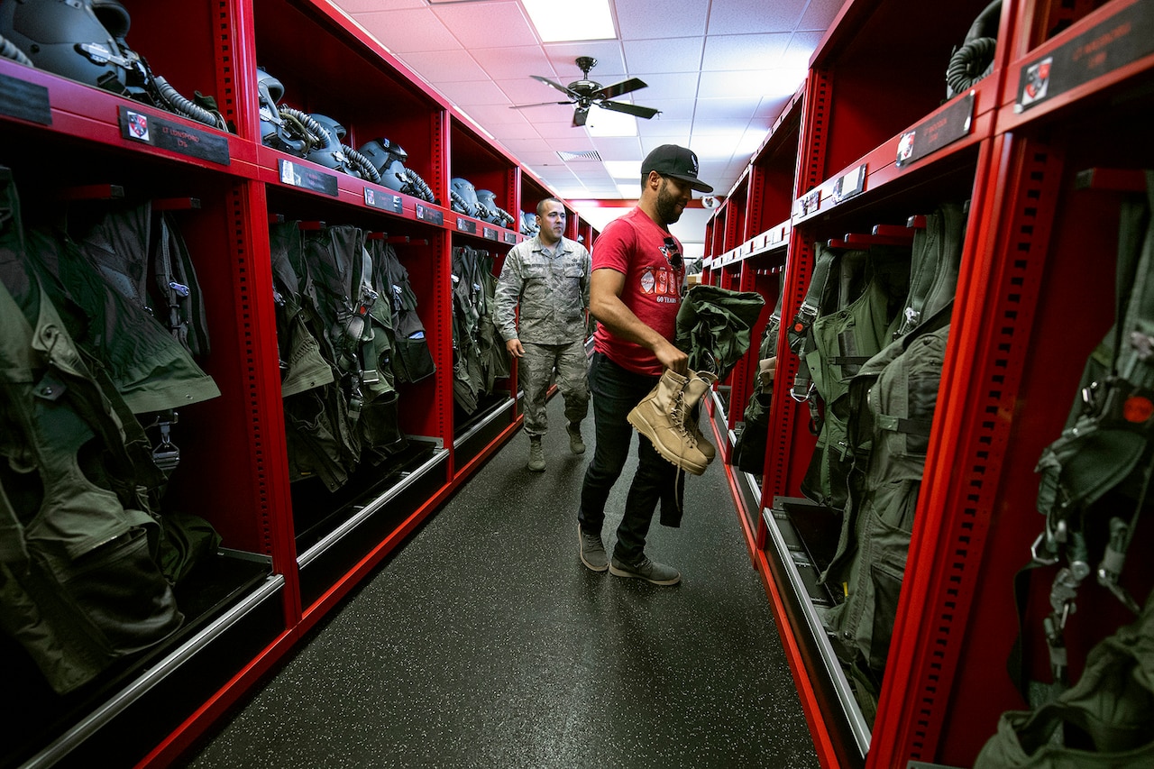 An airman shows a civilian what gear to grab.