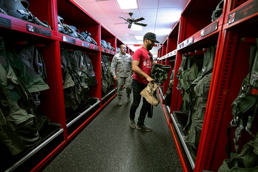 An airman shows a civilian what gear to grab.