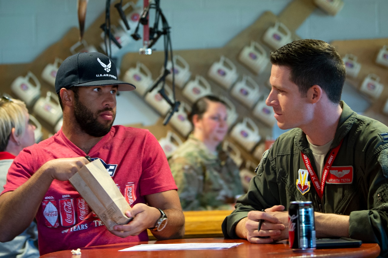 A man eats popcorn while listening to an airman speak.