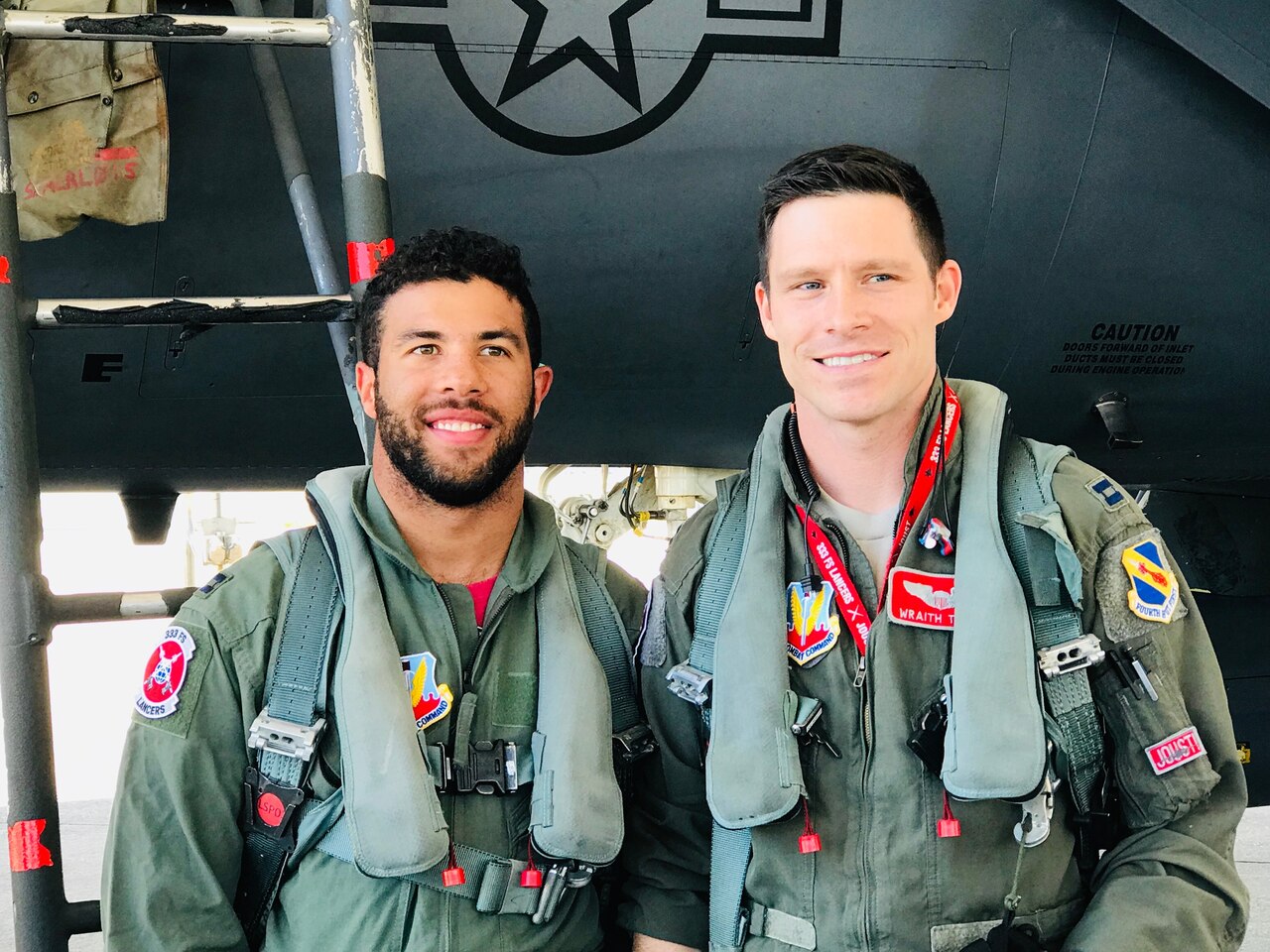 Two men in flight suits stand beside each other.