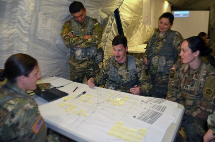 Army Medical Department Center & School, Health Readiness Center of Excellence students participate in a field training exercise for the Captains Career Course at Joint Base San Antonio-Camp Bullis May 7. Sitting clockwise at the table are Capts. Mike Bird, Maureen Mulholland and Kirby Leininger, who are looking at a map of Houston in a scenario in which a hurricane has made landfall on the city. During the exercise, the students put together a support operations plan for a medical battalion that is supporting civil authorities responding to the hurricane. Students in the Captains Career Course undergo nine weeks of training that includes classroom and hands-on training about the Military Decision Making Process, Army Health Systems Support and Force Health Protection doctrine, unit training management, leadership skills and staff officer functions.