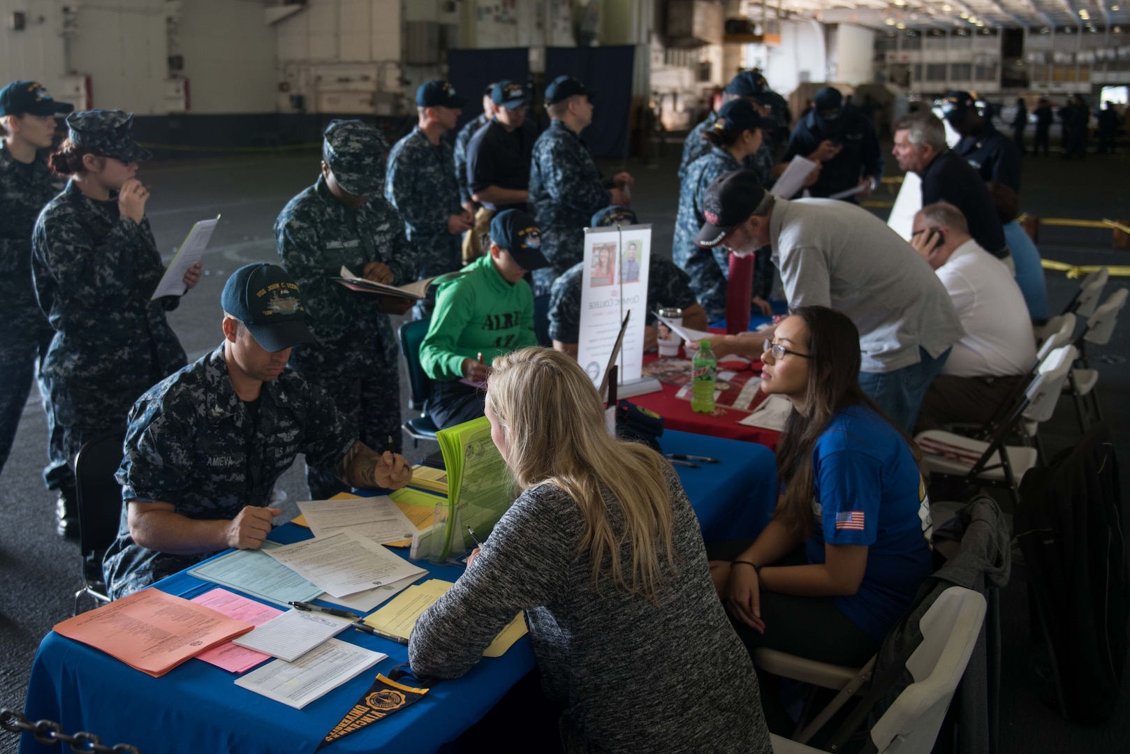 Representatives from Navy College Program for Afloat College Education, or NCPACE, Olympic College, Coast Line Community College and Vincennes University speak to Sailors about educational opportunities during an NCPACE sign-up event in the hangar bay aboard the aircraft carrier USS John C. Stennis (CVN 74) in Bremerton, Washington.