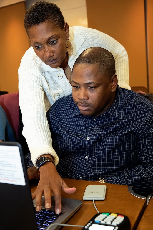 U.S. Army Sgt. 1st Class Cassandra McCulloch, U.S. Army Financial Management Command senior financial management trainer, helps U.S. Army Staff Sgt. Marvin Luke, 4th Financial Management Support Unit disbursing manager, during a USAFMCOM and Federal Reserve Bank of Boston-hosted training session at the Federal Reserve Bank of Boston May 8, 2019.