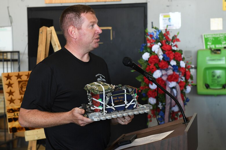 A man holds a miniature model of a heavy aerial delivery cargo unit.