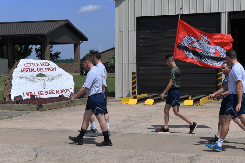 A group of Airmen walk from the left to the right of the frame.