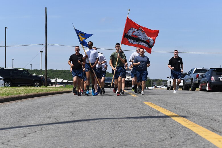 Men and women run down a road in formation.