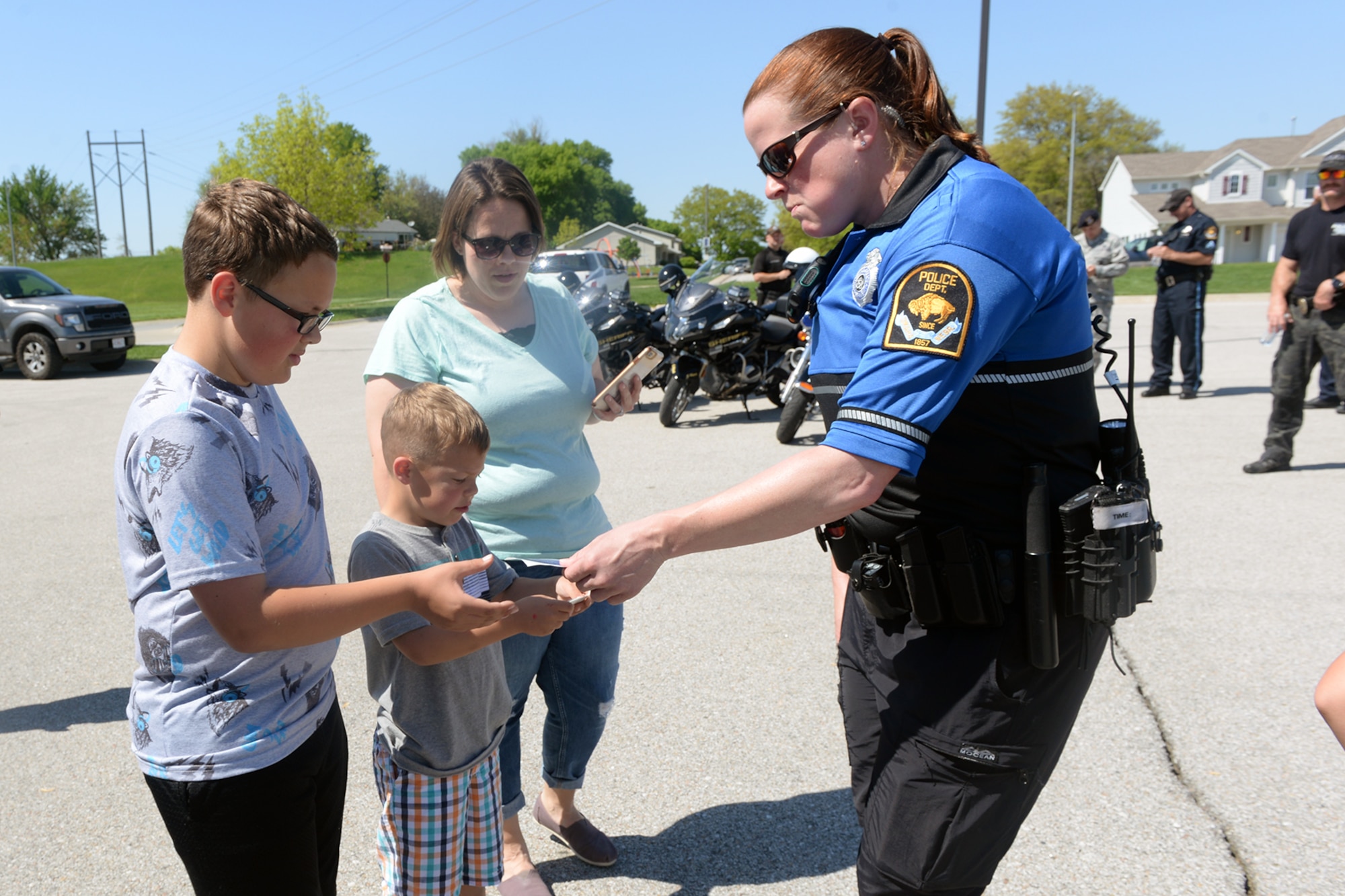Police officer Chris Abbott, Bellevue Police Department, hands out stickers during a Police Week fair May 14, 2019, at Offutt Air Force Base, Nebraska. Police week was established in 1962 by President John F. Kennedy to honor officers. (U.S. Air Force photo by Kendra Williams)