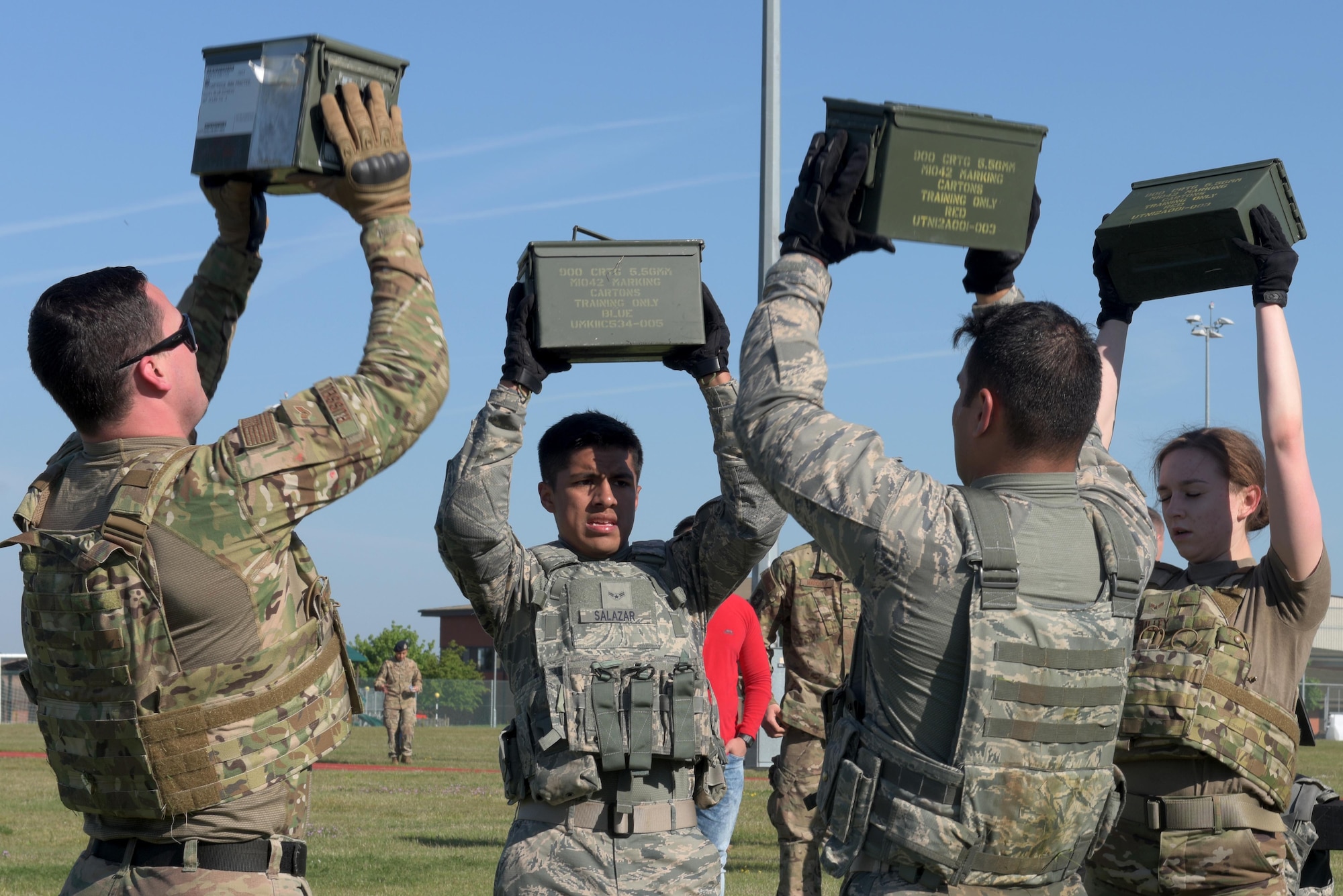 Members of the 100th Security Forces Squadron perform synchronized shoulder presses with ammo containers filled with dirt during the Defenders Challenge at RAF Mildenhall, England, May 15, 2019. The obstacles were to pay tribute to the 14 Defenders who gave their lives in the line of duty since Sept. 11, 2001. (U.S. Air Force photo by Senior Airman Benjamin Cooper)