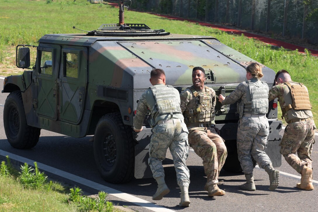 Members of the 100th Security Forces Squadron push a Humvee as part of the Defenders Challenge at RAF Mildenhall, England, May 15, 2019. Obstacles were designed to imitate possible challenges a Defender may face in the line of duty or during a deployment. (U.S. Air Force photo by Senior Airman Benjamin Cooper)