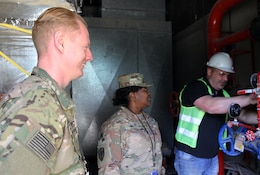 Sgt. 1st Class Michael Armstrong and Master Sgt. Deangelis Taylor, 184th Sustainment Command, observe a contractor working on pipes at Camp Arifjan, Kuwait, Feb. 28, 2019.