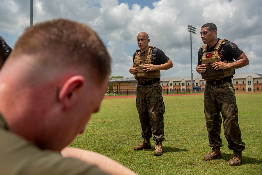 U.S. Marine Corps Staff Sgt. Pedro U. Padilla, center, a chief instructor trainer, and Staff Sgt. David G. Munoz, right, assistant chief instructor trainer both with Marine Aircraft Group 49, 4th Marine Aircraft Wing, Marine Forces Reserve, speak to students with Martial Arts Instructor Course 1-19 after a combat conditioning exercise at Naval Air Station Joint Reserve Base New Orleans on May 20, 2019. To increase readiness and to support the total force, Reserve and active Marines with MARFORRES participate in the Martial Arts Instructor Course.  (U.S. Marine Corps photo by Lance Cpl. Jose Gonzalez)