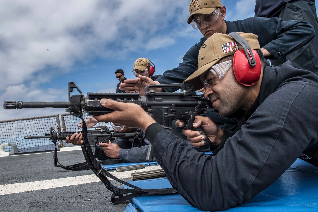 A sailor fires a weapon on a ship.