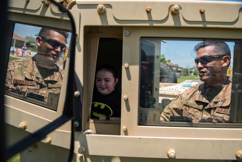 U.S. Air Force Master Sgt. Nicanor Blaustein, 633rd Security Forces Squadron flight chief, shows Liseli Nin Rodriguez, daughter of Senior Airman Anthony Nin Leclerec, how to turn on a Humvee at Bethel Manor, Hampton, Virginia, May 18, 2019. Airmen of the 633rd Security Forces were on site to answer questions about different aspects of this job and the equipment they use. (U.S. Air Force photo by Senior Airman Anthony Nin Leclerec)