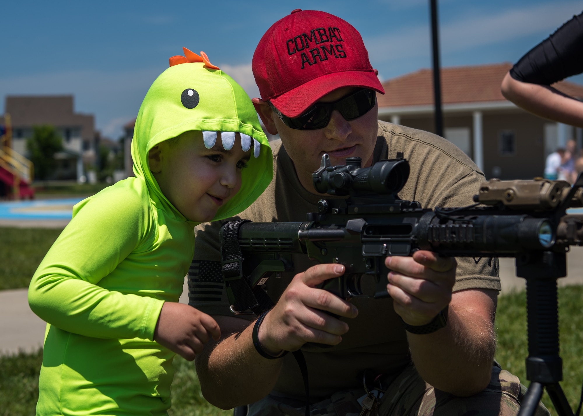 A U.S. Air Force combat arms instructor from the 633rd Security Forces Squadron, shows Matthew Nin Rodriguez, son of Senior Airman Anthony Nin Leclerec, how to look through a scope at Bethel Manor, Hampton, Virginia, May 18, 2019. (U.S. Air Force photo by Senior Airman Anthony Nin Leclerec)