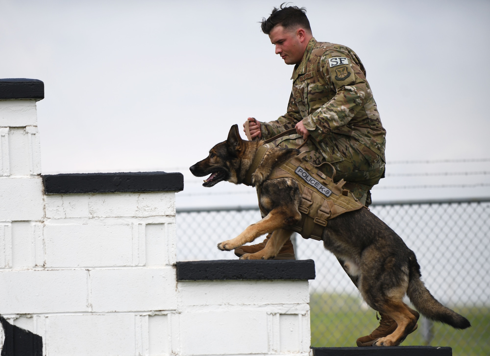 Senior Airman Chase Loggins, a 28th Security Forces Squadron military working dog handler, leads MWD Boris through the obedience course on Ellsworth Air Force Base, S.D., May 16, 2019. Loggins and Boris competed against a police K-9 from the South Dakota Highway Patrol, in recognition of National Police Week. The dogs had to complete the obstacle course without being distracted by the plethora of toys planted throughout the course.  (U.S. Air Force photo by Airman 1st Class Christina Bennett)