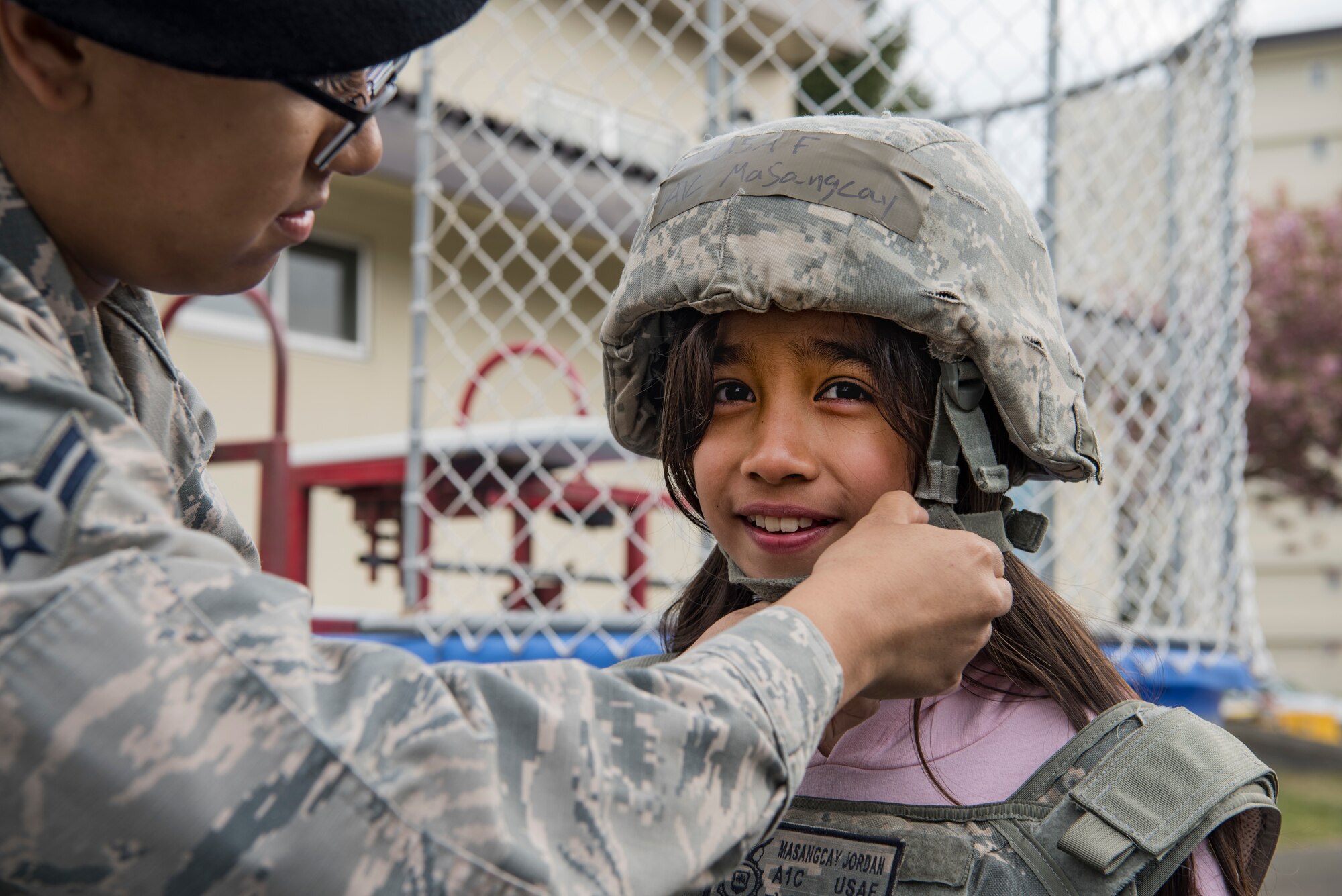 U.S. Air Force Airman 1st Class Aliciana Infante-Crawford, a 35th Security Forces Squadron armory journeyman, helps an attendee try on a helmet during a static display at Misawa Air Base, Japan, May 15, 2019. The National Police Week static display event honored police officers who died in the line of duty. The 35th SFS hosted various events such as a K-9 demonstration, ruck march and a public show with local Japanese police officers. (U.S. Air Force photo by Airman 1st Class Xiomara M. Martinez)