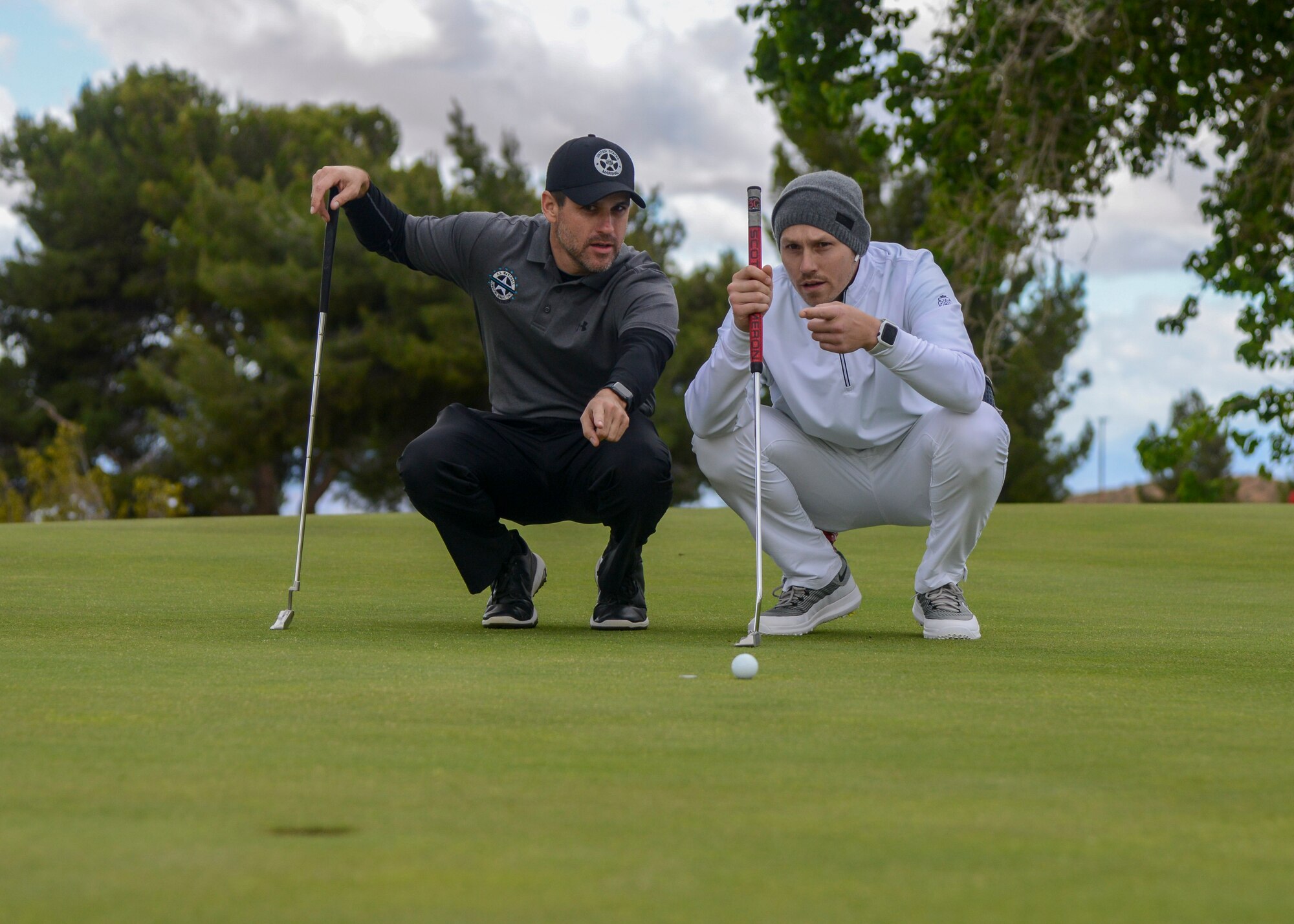 U.S. Marshal Zack Tyler and Joey Gonzalez discussing putting strategy during a golf tournament during Police Week, at Edwards Air Force Base, California, May 14. Police Week is observed May 13-17. (U.S. Air Force photo by Giancarlo Casem)