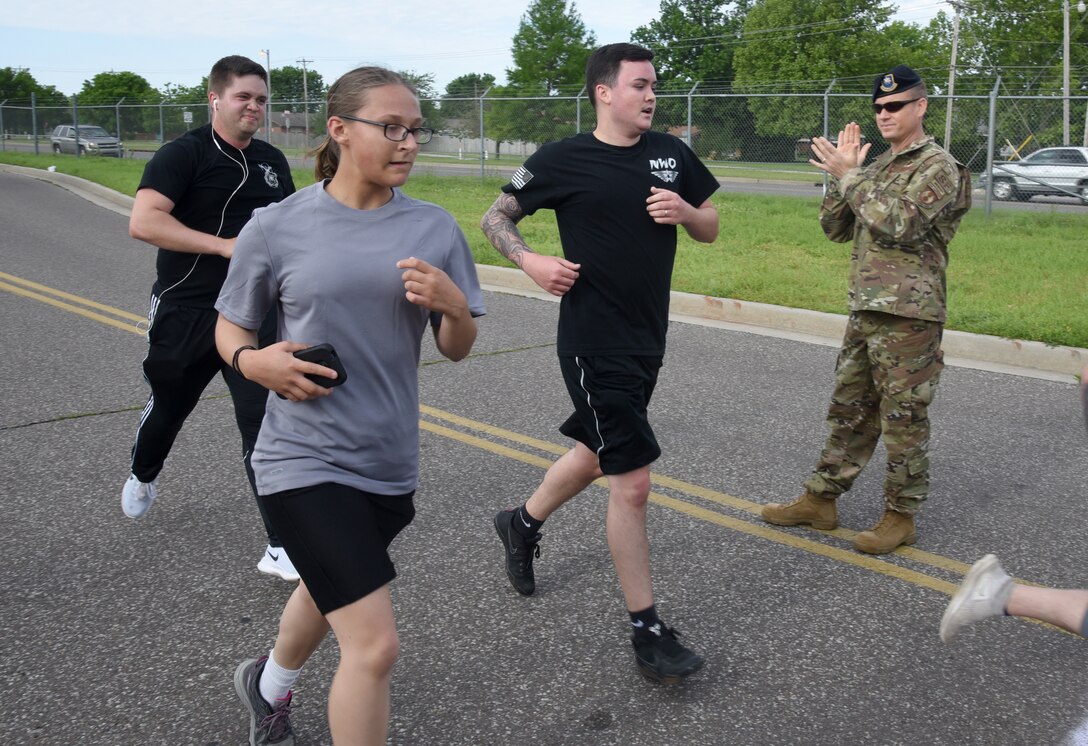 72nd Security Forces Squadron Commander Lt. Col. Tyrell Mayfield applauds runners as they cross the finish line of the Defender 5K May 14. The squadron recognized National Police Week with Reveille, golf and bowling tournaments, the 5K and a Memorial Service. (U.S. Air Force photo/Kelly White)