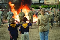 Boy scouts salute an American flag as it is retired in flames