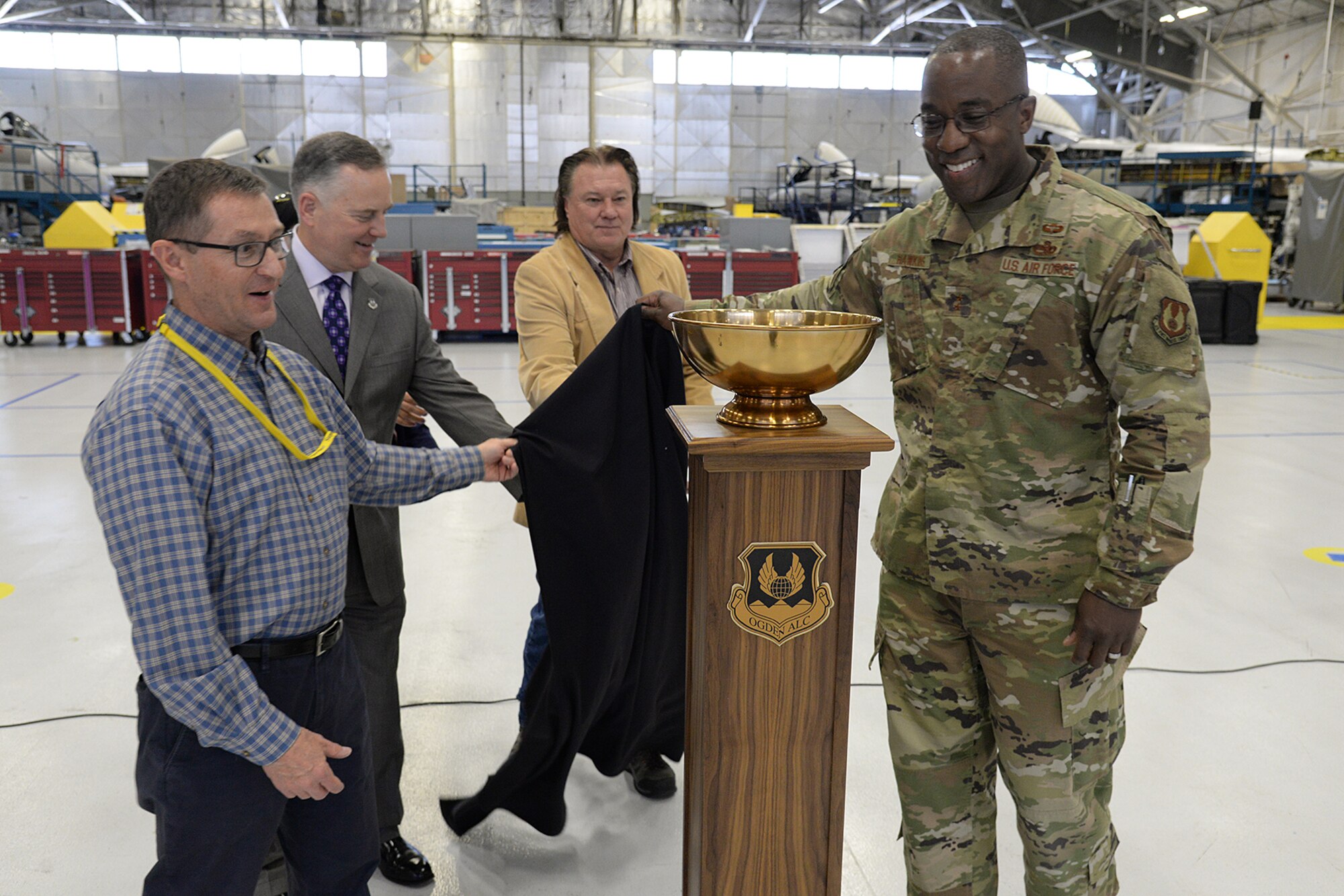 Stephen Zaiser, 571th Aircraft Maintenance Squadron director,  Eric Fox, Ogden Air Logistics Complex vice director, Troy Tingey, Union president, and Maj. Gen. Stacey Hawkins, OO-ALC commander, unveil the L-A-M-P Award trophy on May 9, at Hill Air Force Base, Utah. The new award is a traveling trophy which will be presented each month to the Complex’s most outstanding unit.