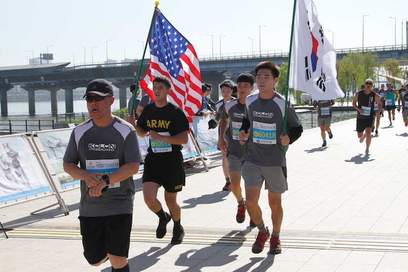 Runners take part in a race, with two carrying U.S. and South Korean flags.