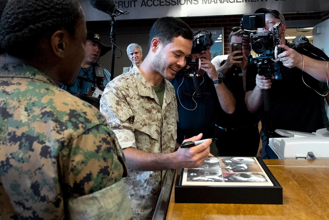 A man smiles while signing a photo.