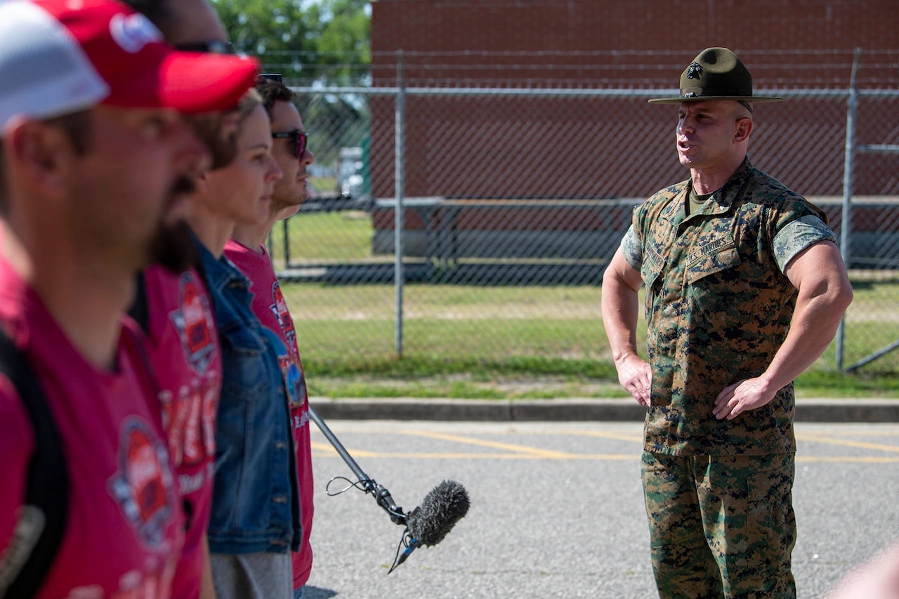 A Marine Corps drill instructor yells at four recruits.