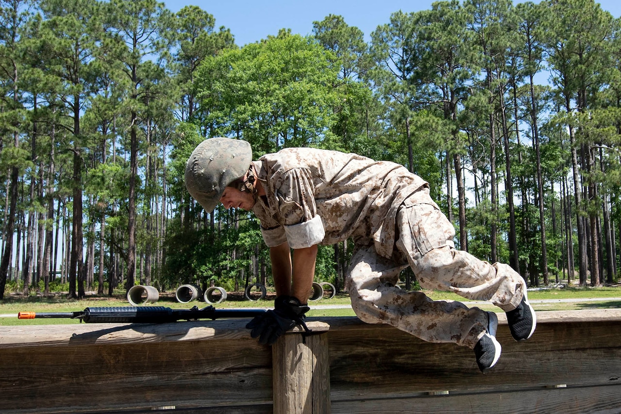 A man hops over a wooden beam.