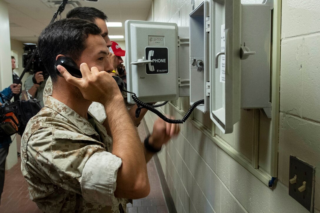 A man holds a landline phone to his ear.