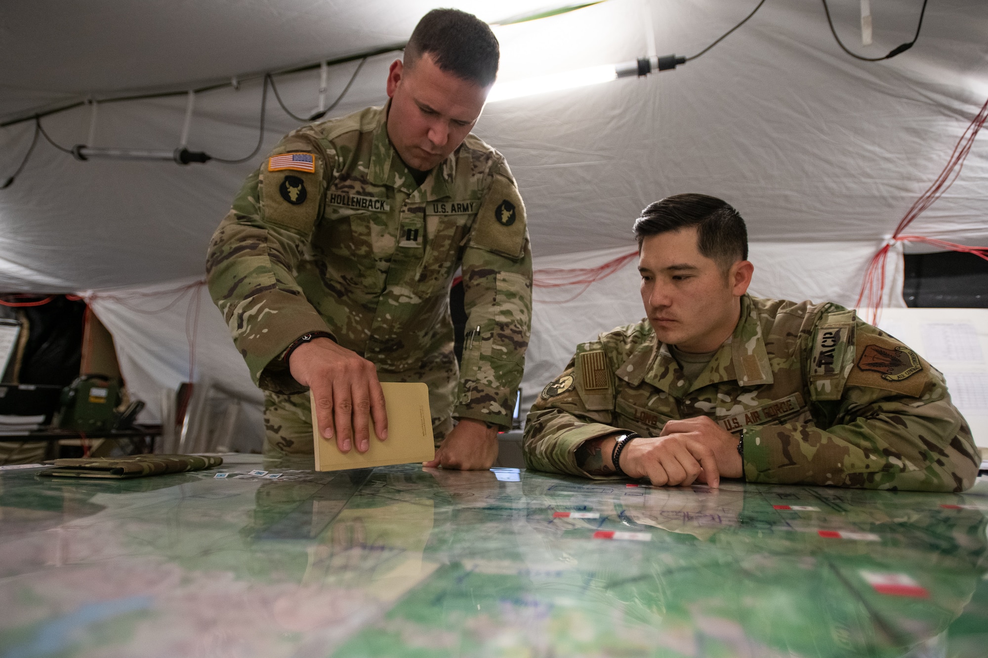 Minnesota Army National Guardsman Capt. Charles Hollenback, brigade fires direction officer with the 1st Armored Brigade Combat Team, 34th Infantry Division (1/34th ABCT), and Oklahoma Air National Guardsman Staff Sgt. Jeremy Long, a brigade tactical air control party team sergeant assigned to the 146th Air Support Operations Squadron (146th ASOS), discuss close air support tactics on map during a brigade Warfighter exercise (WFX 19-12) held at Camp Ripley near Little Falls, Minn., May 13, 2019. The 24-hour continuous, graded exercise, which is the second of three exercises that U.S. Army and National Guard units are required to complete before deployment, tests the units at the brigade level before heading to the final and more applied exercise at the National Training Center (NTC), in Fort Irwin, Calif. (U.S. Air National Guard photo by Tech. Sgt. Kasey M. Phipps)