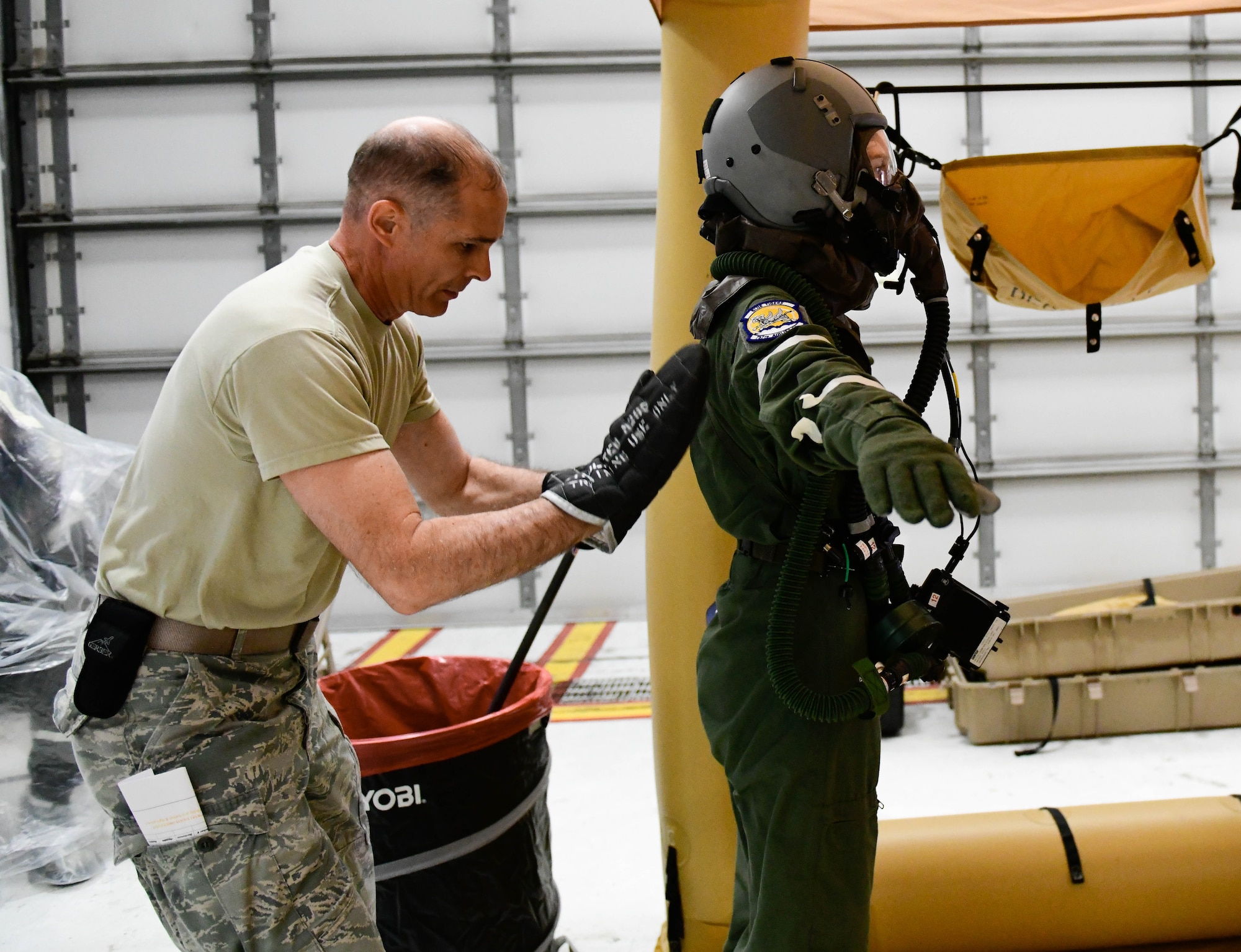 Master Sgt. Phil Walsh, aircrew flight equipment supervisor assigned to the 910th Operations Support Squadron, pats down Senior Airman Kaleb Walker, a loadmaster assigned to the 757th Airlift Squadron with a decontamination mitt on May 4, 2019.
