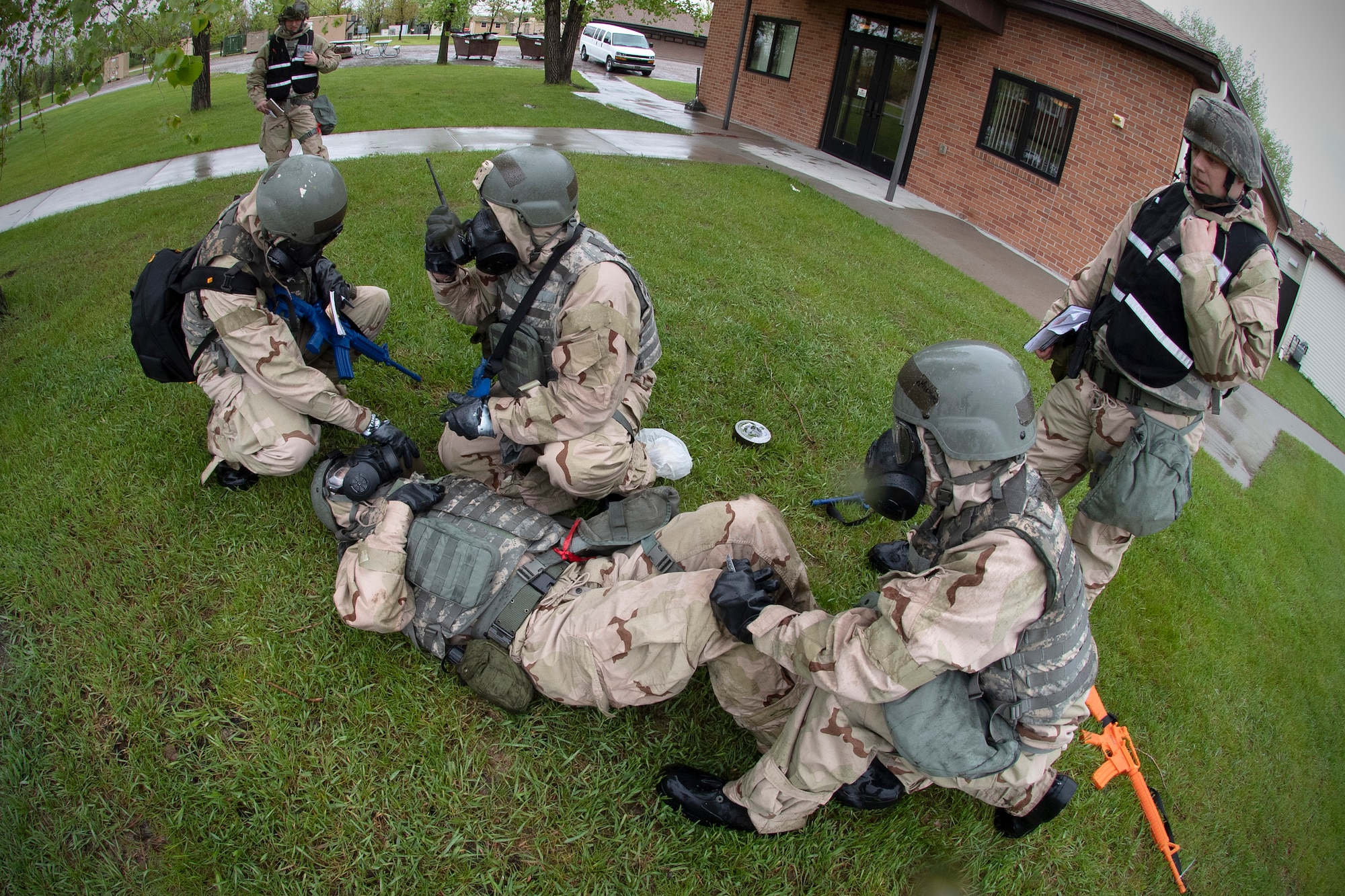 Airman 1st Class Devin Riggs, 319th Logistics Readiness ground transportation apprentice, center, displays signs of fatigue and dizziness after being contaminated during a performance and accountability report May 22, 2019, on the Air National Guard Base in Fargo, North Dakota. Riggs was part of a PAR team during exercise Summer Viking 19-01. His team reacted instantly with self-aid and buddy care, and decontamination efforts. (U.S. Air Force photo by Senior Airman Elora J. Martinez)