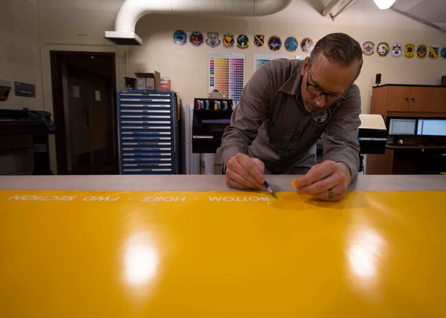 A civilian peels off stencils from a sheet of paper.