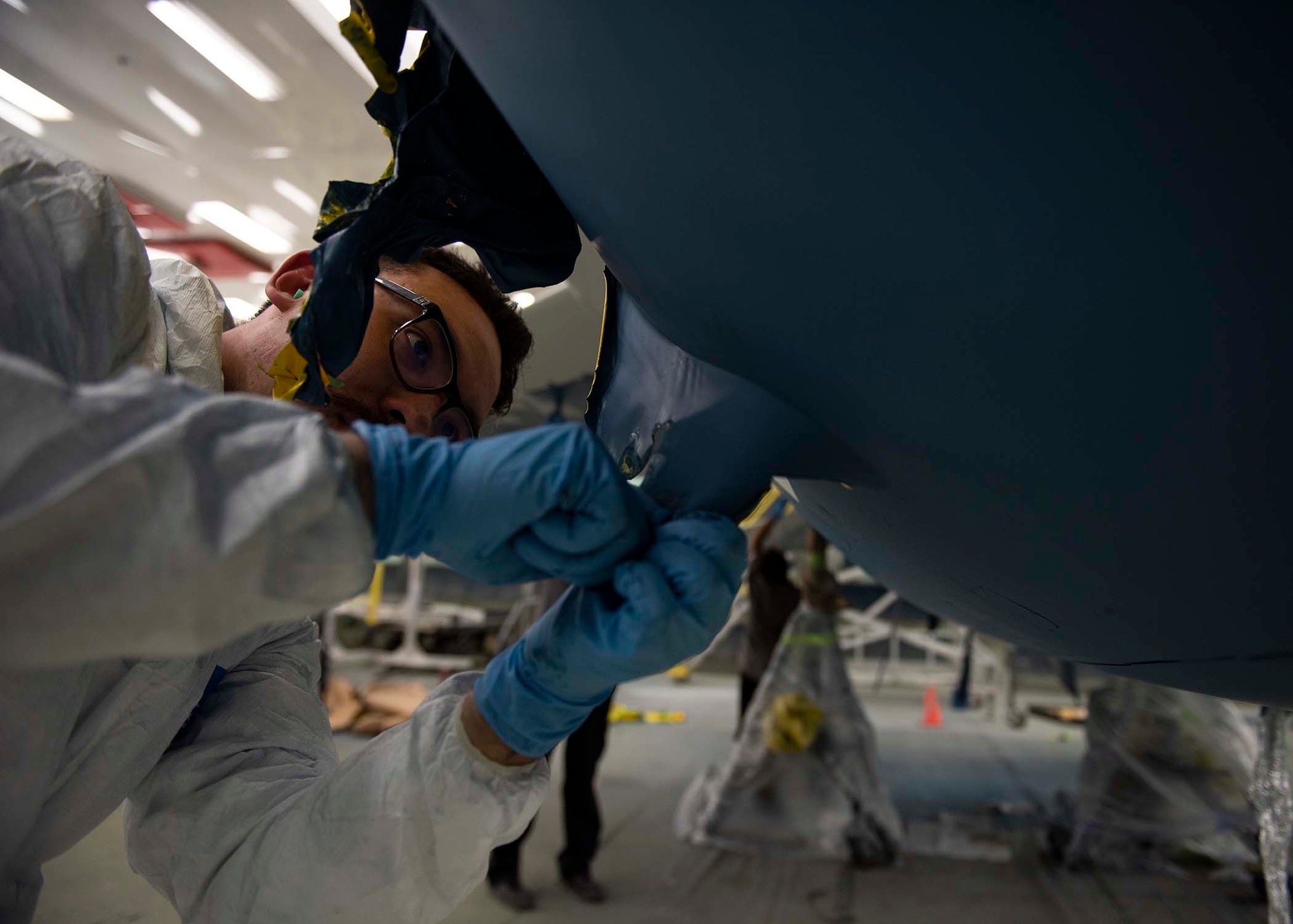 A civilian pulls masking tape off of an F-16 Fighting Falcon fighter jet.