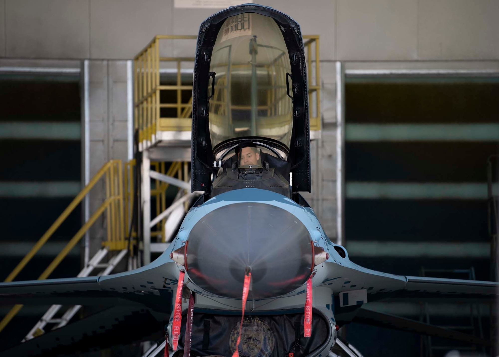 An Airman sits in the cockpit of an F-16 Fighting Falcon fighter jet.
