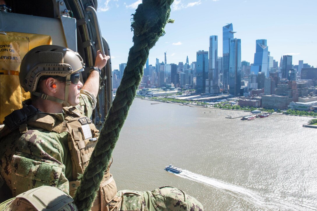 A sailor checks out the city skyline from a helicopter.