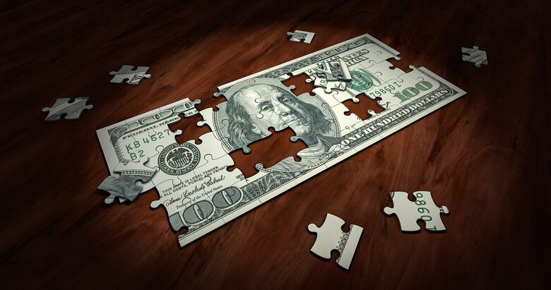 $50 bill as unassembled puzzle on wooden table