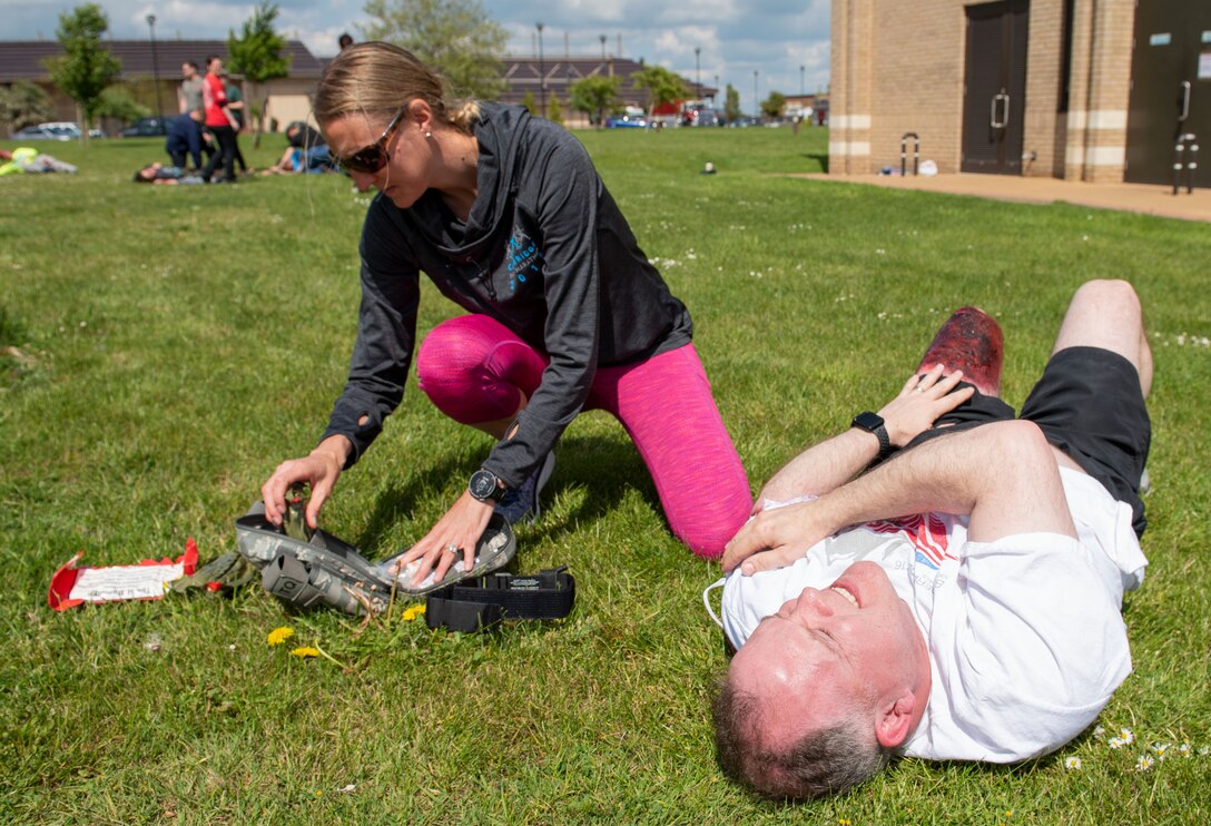 Carissa Rutt, 501st Combat Support Wing health promotions coordinator assists Lt. Col. Alan Williamson, a simulated casualty, in the first-ever joint mass-casualty medical training between the 423rd Medical Squadron and the 423rd Civil Engineer Squadron at RAF Alconbury, England, May 21, 2019. The training between medical specialists and firefighters enhanced their rapid response to mass-casualty situations. (U.S. Air Force photo by Airman 1st Class Jennifer Zima)